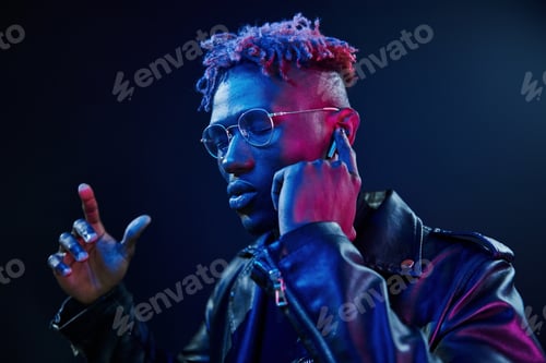Preview: Listening to the music. Futuristic neon lighting. Young african american man in the studio