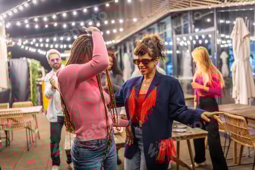 Visualização: Mulheres dançando ao lado de amigos na festa noturna