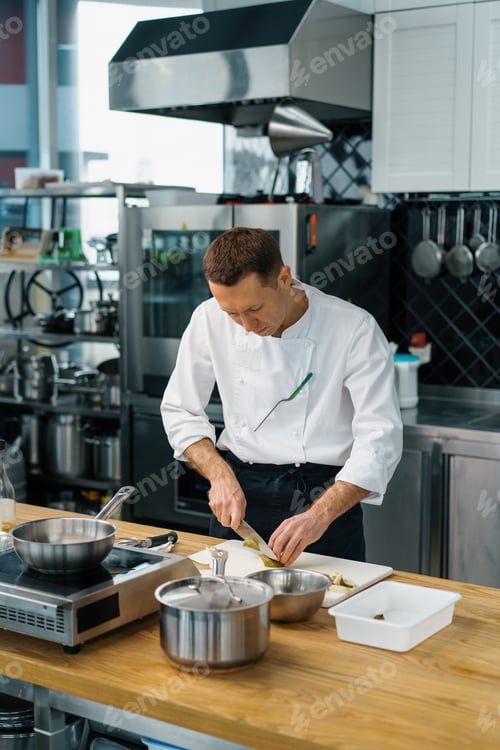 Preview: professional chef cutting fruit with knife to prepare oatmeal breakfast healthy food concept