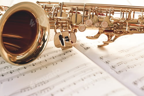 Preview: Closeup of a beautiful and shiny golden saxophone lying on music notes
