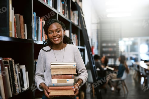Preview: Portrait of a happy young woman carrying books in a library at college