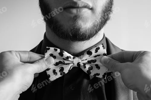 Preview: Man Adjusts Bow Tie with Mustache Pattern
