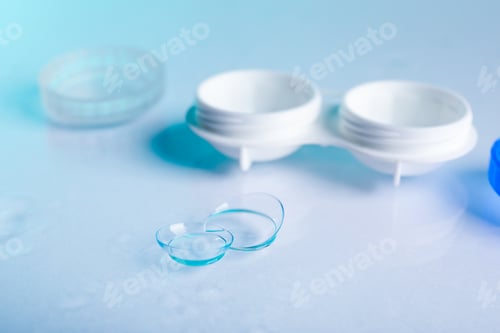 Preview: Pair of contact lenses and container on light mirror surface, closeup