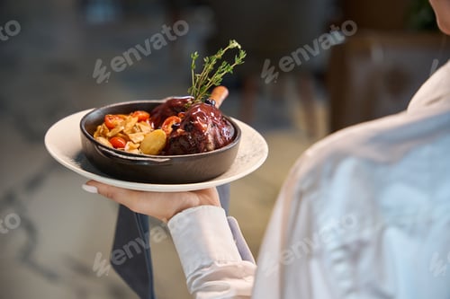 Preview: Waitress serves meat with vegetables in a serving pan