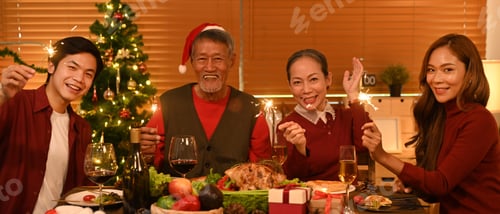 Preview: Group of people with sparklers having fun celebrating Christmas at dining table.