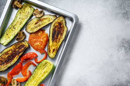 Preview: Roasted vegetables on a baking pan. White background. Top view. Copy space