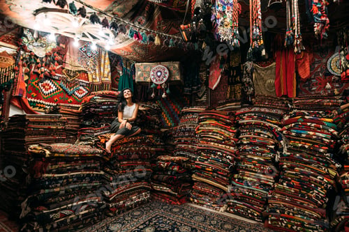 Preview: Girl in a carpet store. Happy woman customer choosing colored carpet in carpet store