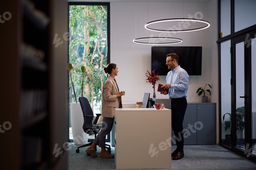 Visualização: Colegas de trabalho felizes conversando enquanto trabalham no escritório.