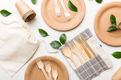 Preview: empty reusable disposable eco-friendly plates, utensils on colored table background. top view.
