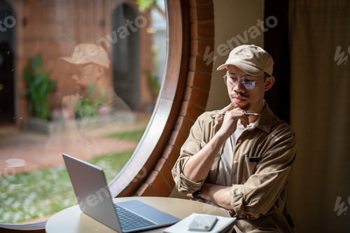Preview: Thoughtful man in casual outfit working on laptop by window