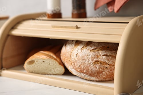Preview: Wooden bread basket with freshly baked loaves on white marble table in kitchen, closeup