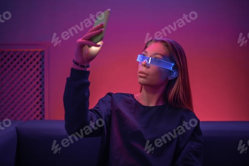 Preview: Young woman in glowing glasses uses the phone