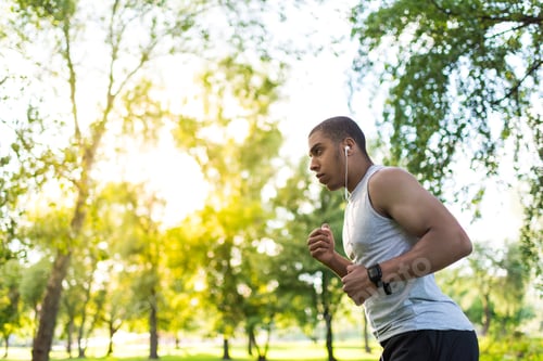 Preview: side view of handsome young african american man in sportswear running in park
