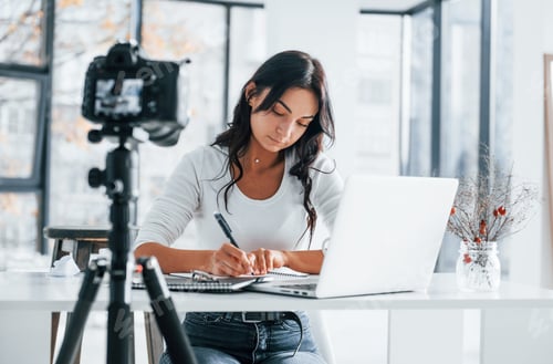Preview: Camera recording girl. Young female freelancer working indoors in the office at daytime