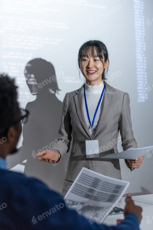 Preview: Happy young Asian female with papers standing by interactive whiteboard with data