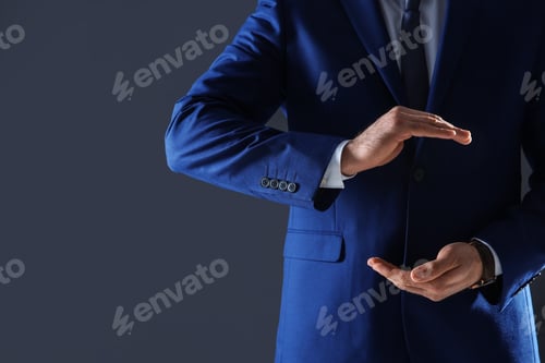Preview: Businessman holding something in hands on dark background