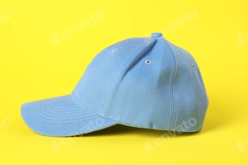 Preview: One light blue baseball cap on yellow background, closeup. Mockup for design