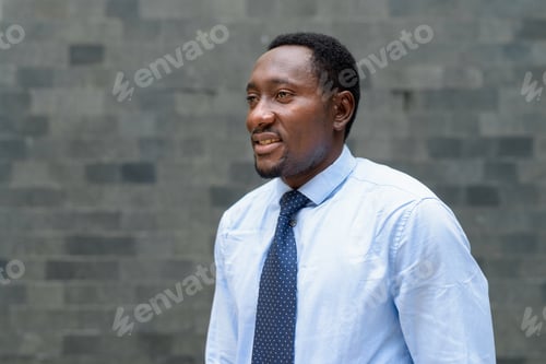 Preview: Portrait of handsome African businessman in city thinking