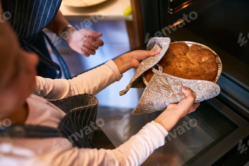 Preview: Cropped shot of a little girl removing a freshly baked cake from the oven at home