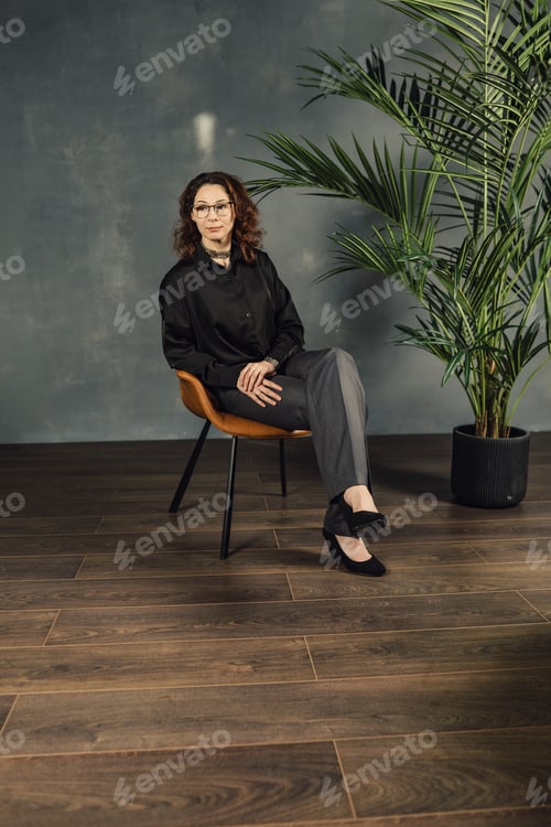 Preview: Business woman sitting cross-legged on a chair