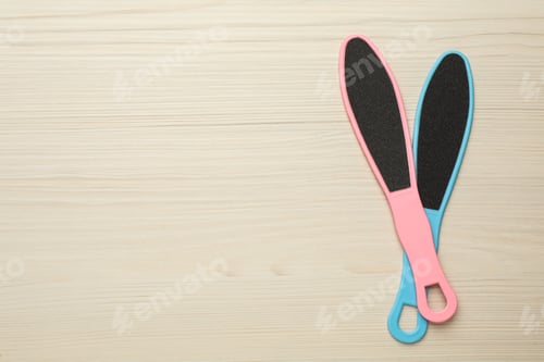 Preview: Colorful foot files on white wooden table, flat lay with space for text. Pedicure tools