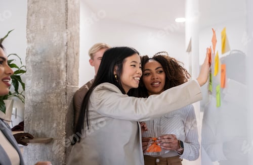 Preview: Businesswomen planning strategy using adhesive notes on whiteboard in office