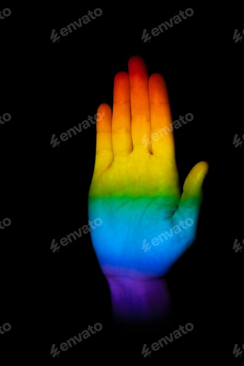 Preview: Hand making a stop gesture illuminated with the LGBT pride flag on a black background
