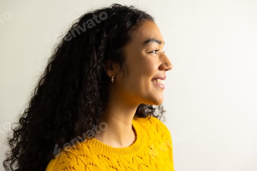 Preview: Profile of happy biracial woman in yellow sweater at home