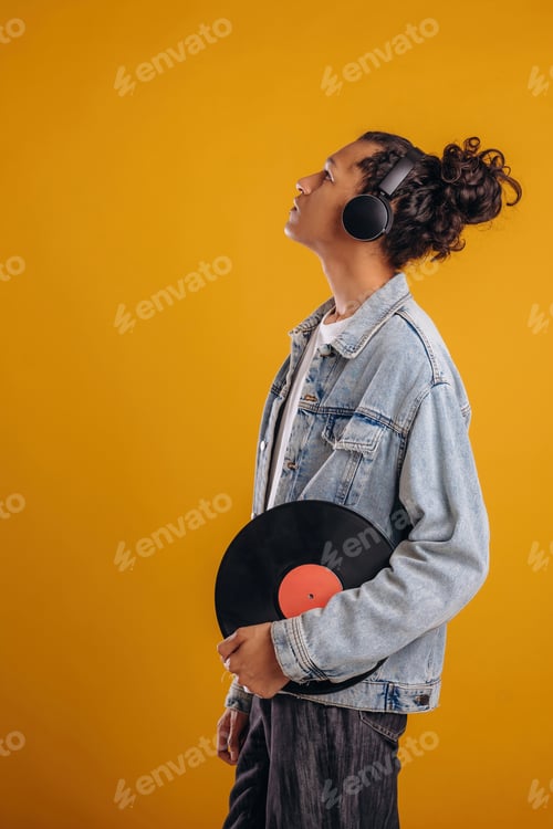 Preview: Retro vinyl record in hand. Young guy is against yellow background