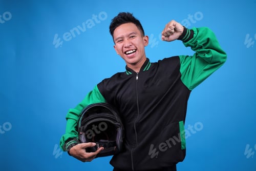 Preview: Smiling Man Holding Motorcycle Helmet Against Blue Backdrop