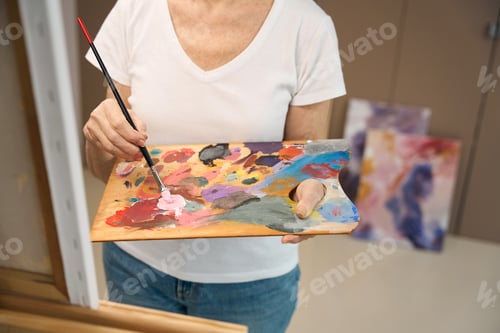 Preview: Elderly woman holds a palette and brush in her hands