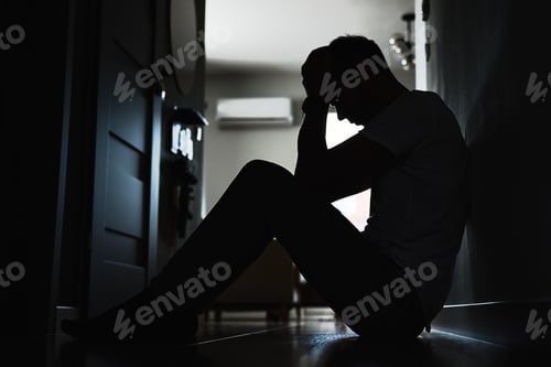 Preview: Depressed man sitting on floor in dark room