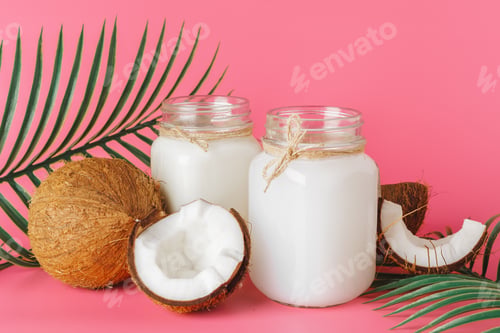 Preview: Cracked coco and coconut milk in glass on bright pink background
