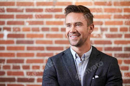 Preview: Young Businessman Standing Against Brick Wall In Modern Office