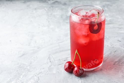 Preview: Tasty cherry soda with ice cubes and berries on grey textured table, closeup. Space for text