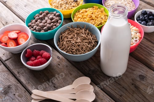 Preview: High angle view of various cereal bowls with milk and berry fruits arranged on table