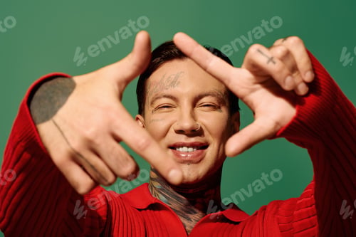 Preview: A joyful young man with vibrant tattoos expresses himself against a colorful background