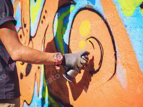 Visualização: Grafiteiro pintando na parede da rua. Mão masculina com spray de aerossol