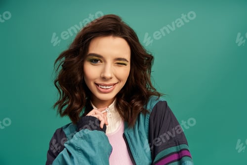 Preview: Charming young woman in bold sporty look poses confidently against turquoise backdrop