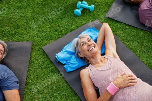 Preview: Senior beautiful woman relaxing on grass after workout