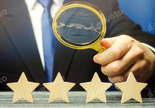 Preview: A man holds a magnifying glass over four stars. The evaluation of visitors.