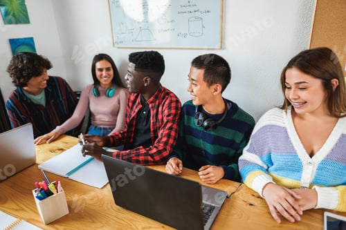 Preview: Multiracial students using laptop computers while studying together inside library