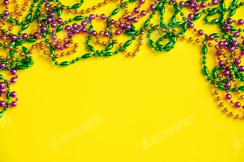 Preview: Mardi Gras concept. Multicolored beads on yellow background. Festive carnival symbols.