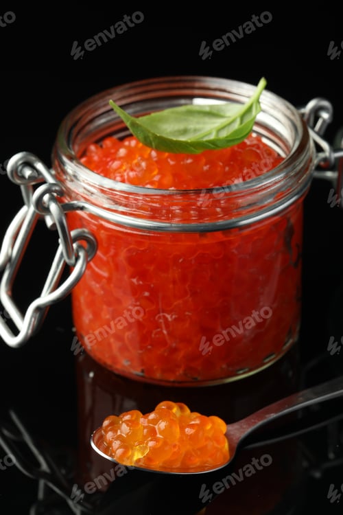 Preview: Delicious red caviar and basil leaf on black background