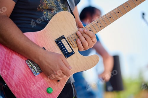 Preview: Rock band performing with vibrant guitar on stage during outdoor event