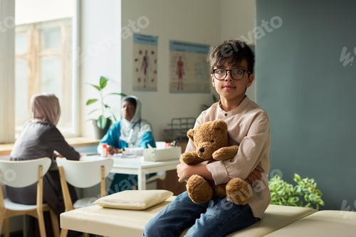 Preview: Young Boy Holding Teddy Bear in Medical Waiting Room