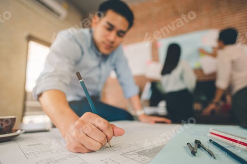 Preview: Close up of male architect hands writing model on the desk. Blurred behind team of engineer