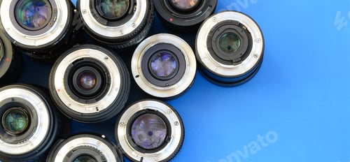 Preview: Several photographic lenses lie on a bright blue background. Space for text