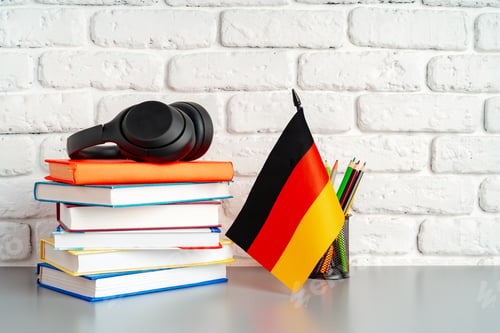 Preview: Stack of books and flag of Germany on desk. German language learning concept