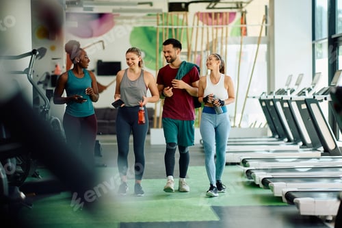 Preview: Happy athletic friends talking while walking through a gym after sports training.